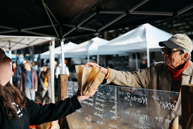 Bodhi vendor handing a paper bag at an outdoor market